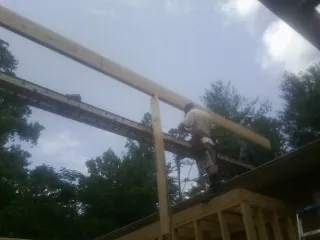 Carpenter setting a ridge beam over a new addition frame — Ice Dam Removal by Roofing Brothers in Harmans