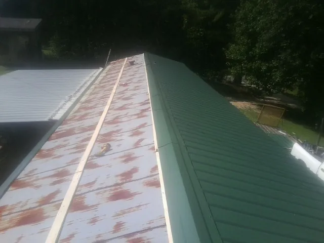Old rusted panels beside newly installed green metal roofing — Wind Damage Roof Repair by Roofing Brothers in Harmans