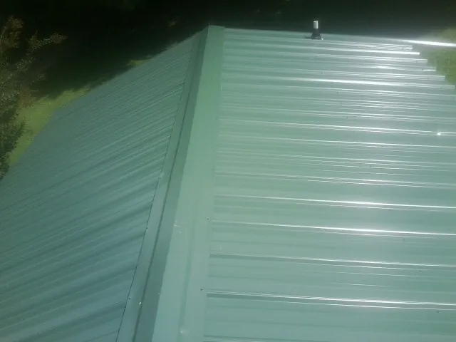 New green metal panels meeting at the ridge of a roof — Flat Roof Repair work by our crew in Harmans