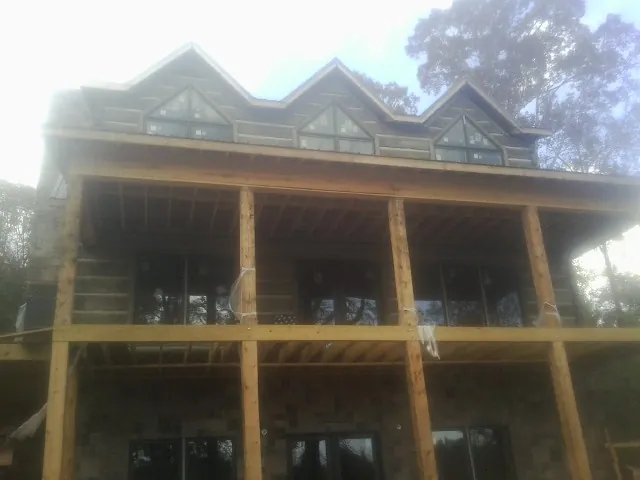 Dormers and porch framing on a large log home under construction — Roof Coating work by our crew in Harmans