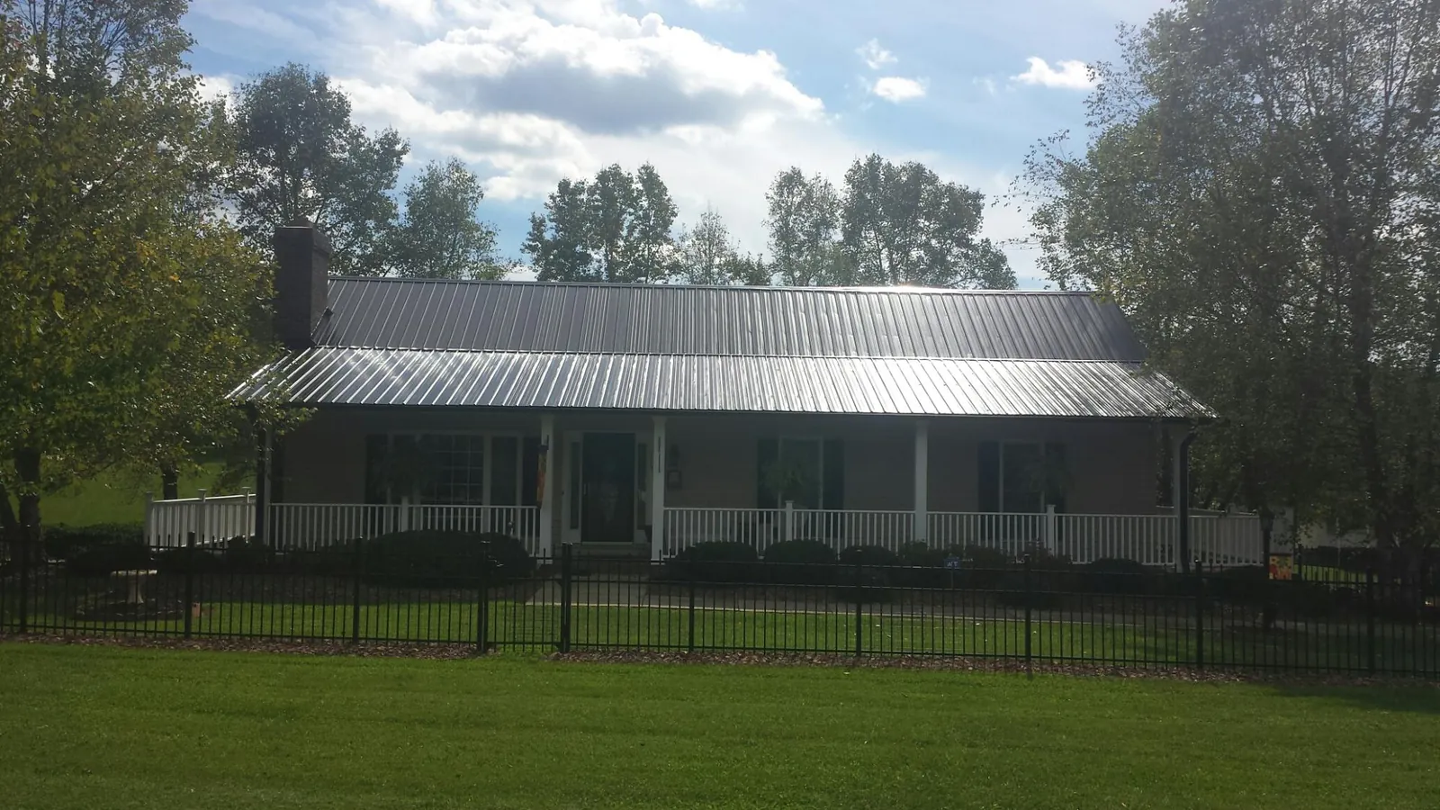 Gray metal roof on a brick ranch with a full width front porch — Gutter Guard Installation work by our crew in Harmans