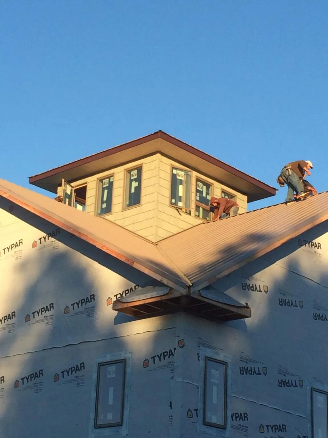 Roofers working around a rooftop cupola on a new metal roof at sunset — Roof Waterproofing in Harmans by Roofing Brothers